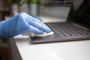Wischen von Laptop-Tastatur mit Desinfektionstüchern