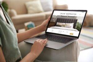 Frau benutzt Laptop, um Wohnung von zu Hause aus zu buchen, Nahaufnahme