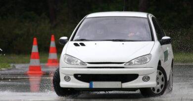 Ein weißes Auto absolviert eine Notbremsung auf nasser Fahrbahn beim Zwei-Phasen-Kurs Winterthur. Verkehrshütchen markieren die Strecke.