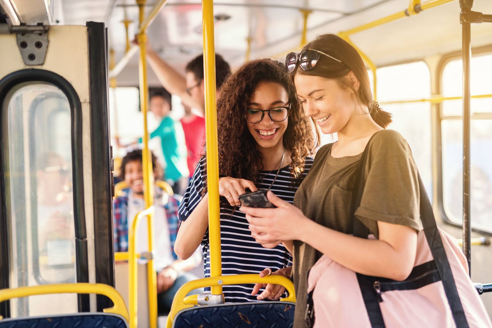 Junge Frauen nutzen Handy im Bus | Nahverkehr Abo