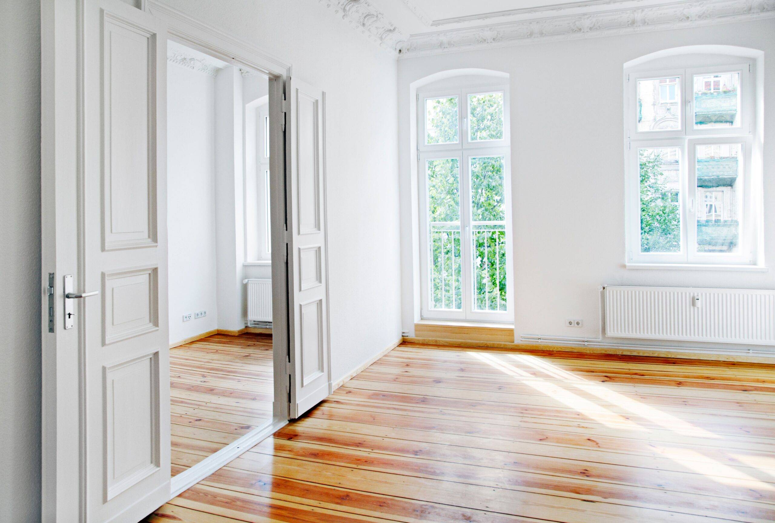 Altbausanierung Berlin: Frisch sanierter Altbau mit hohen Decken, Holzboden und doppelflügeliger Tür im Tageslicht