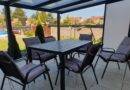 Moderne Terrassenüberdachung Berlin mit Sitzgruppe im gepflegten Garten