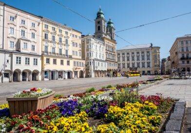 Linzer Hauptplatz mit historischen Häusern und bunten Blumenbeeten an einem sonnigen Frühlingstag