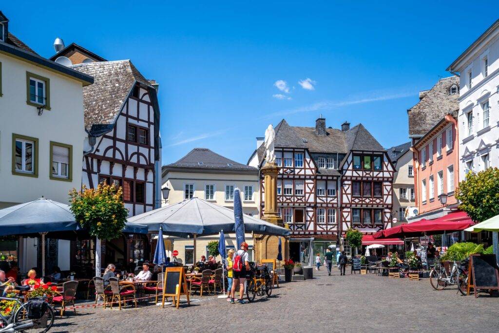 Historischer Marktplatz mit Fachwerkhaeusern, Cafes und Menschen bei Sonnenschein in einer deutschen Altstadt