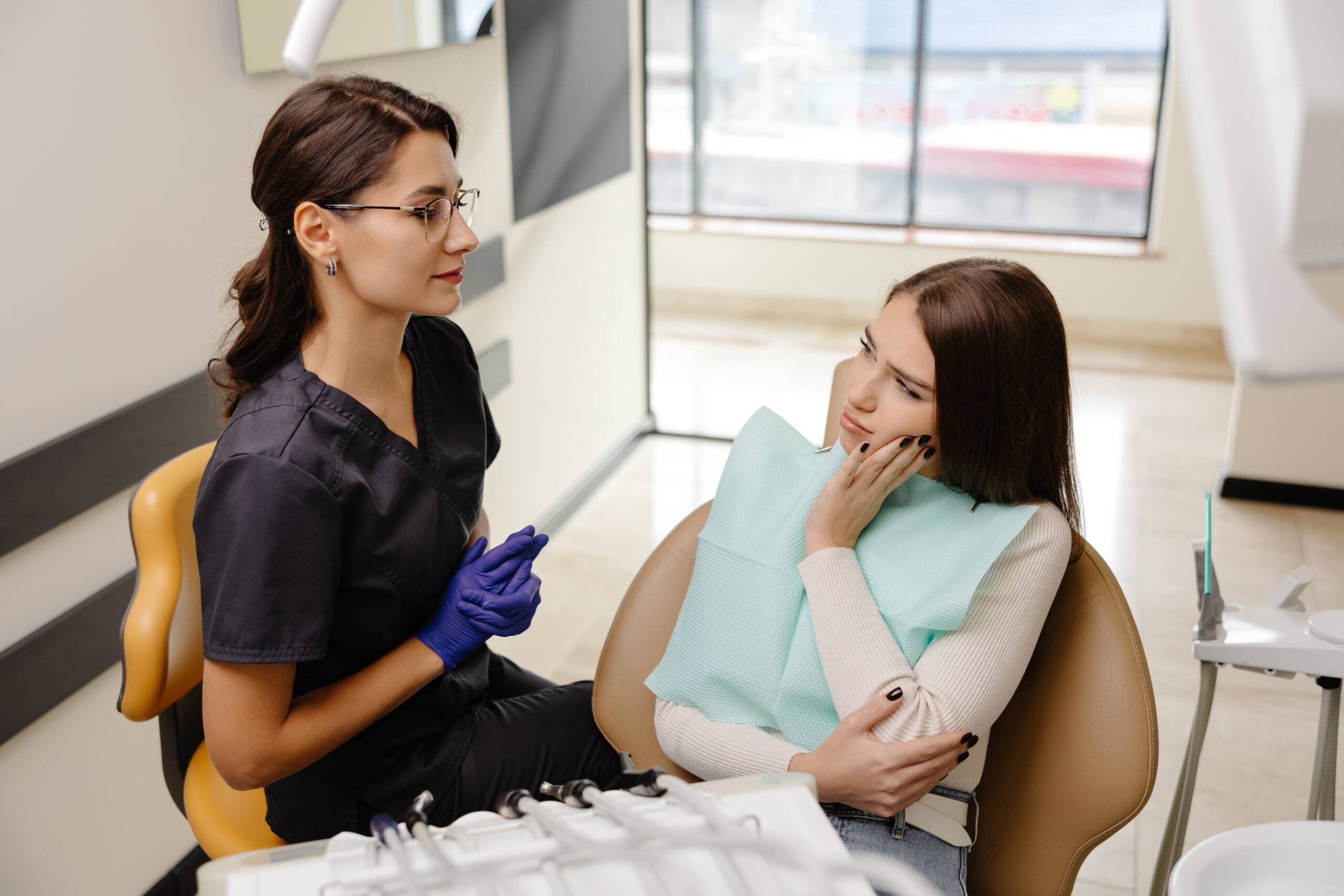 Eine Zahnpatientin mit Schmerzen spricht mit einer Aerztin in einer Praxis in Essen – Beratung durch erfahrene Kieferorthopaedin