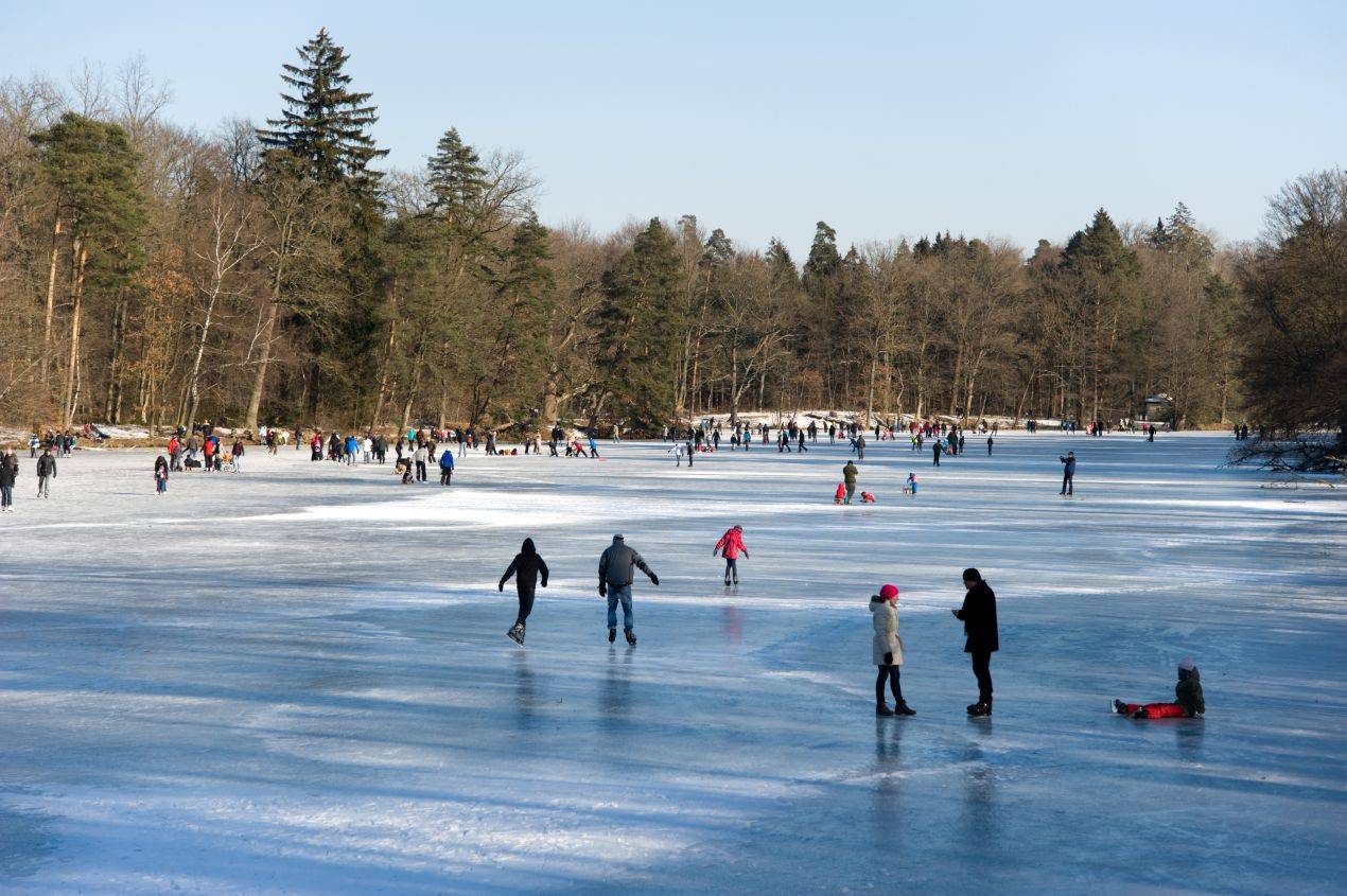 Menschen beim Eislaufen auf einem zugefrorenen See – ideales Ausflugsziel für Schlittschuhe und winterliche Bewegung