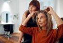 Frau im Friseursalon zeigt auf ihr feines Haar und erhält Beratung für mehr Volumen mit Extensions