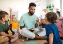 Erzieher sitzt mit Kindern im Kreis und liest vor – Symbolbild fuer Kita Assistenz und paedagogische Unterstuetzung im Kindergarten
